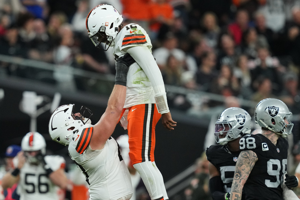 Cleveland Browns guard Wyatt Teller (77) holds up Cleveland Browns quarterback Shedeur Sanders (12) after Sanders threw a touchdown pass against the Las Vegas Raiders during the second half of an NFL football game Sunday, Nov. 23, 2025, in Las Vegas. (AP Photo/Candice Ward)
