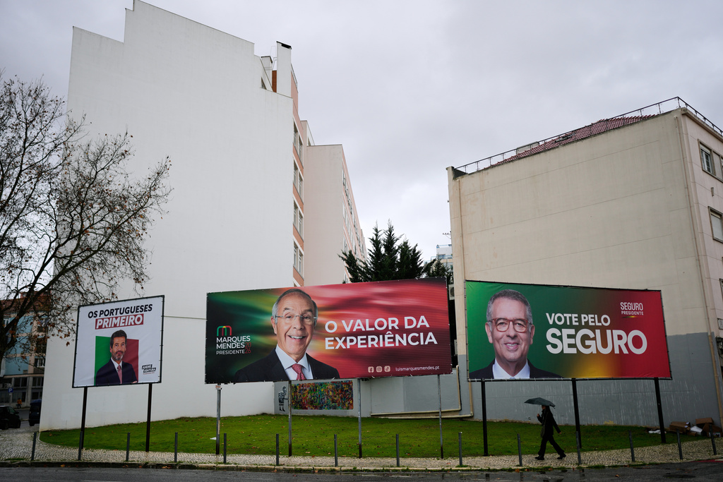 A person walks past presidential election campaign billboards for candidates Andre Ventura of the populist Chega party, Luis Marques Mendes from the center-right Social Democratic Party and Antonio Jose Seguro of the center-left Socialist Party, in Lisbon, Friday, Jan. 2, 2026. (AP Photo/Armando Franca)