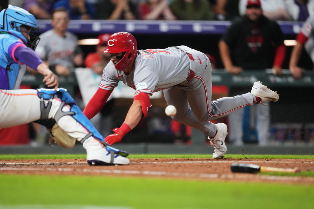 Colorado Rockies catcher Hunter Goodman, left, fields the throw as Cincinnati Reds' Spencer Steer slides safely into home plate to notch an inside-the-park home run off Colorado relief pitcher Jeff Criswell in the eighth inning of a baseball game Friday, July 17, 2026, in Denver. (AP Photo/David Zalubowski)