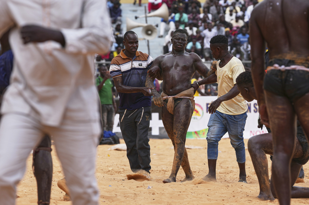 A wrestler is taken off the pitch after a match at the national wrestling arena in Dakar, Senegal, Sunday, March 29, 2026. (AP Photo/Misper Apawu)
