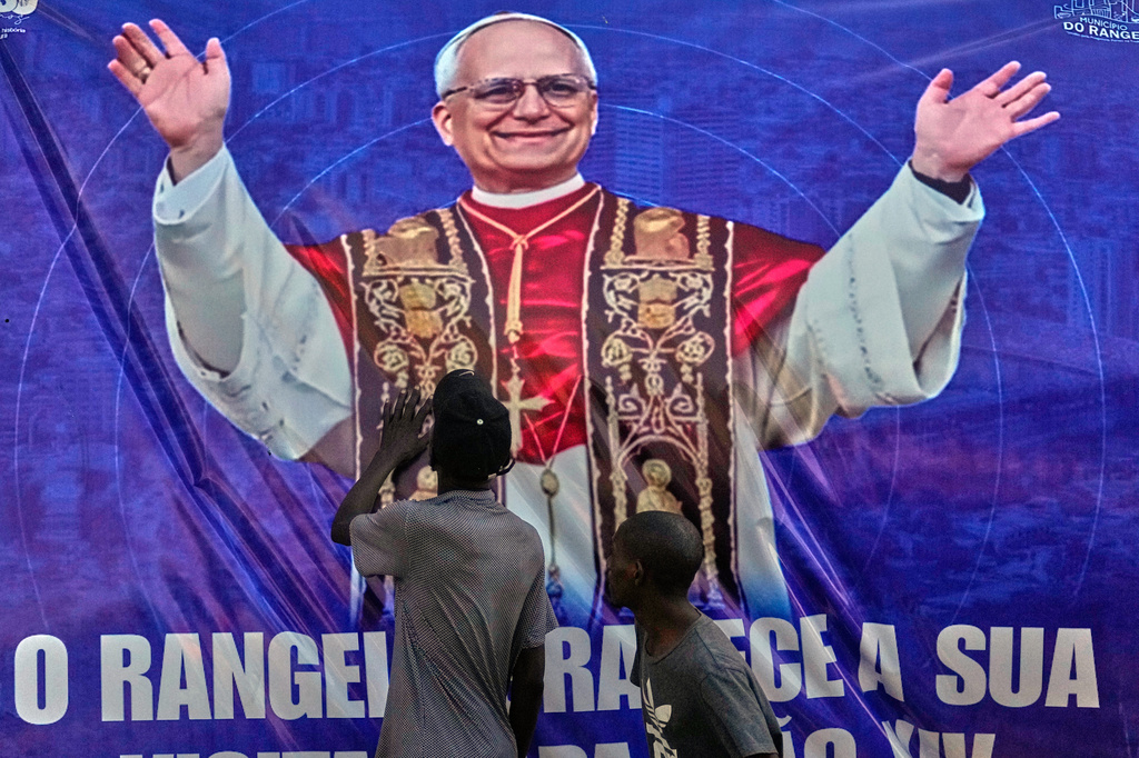 People touch a banner bearing an image of Pope Leo XIV in Luanda, Angola, Monday, April 20, 2026. (AP Photo/Themba Hadebe)