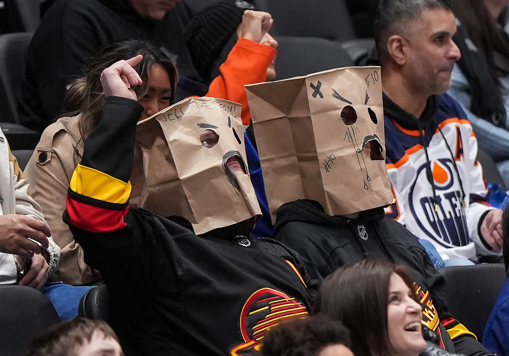 Vancouver Canucks fans wear paper bags on their heads during the third period of a 6-0 loss to the Edmonton Oilers during an NHL hockey game, in Vancouver, on Saturday, Jan. 17, 2026. (Darryl Dyck/The Canadian Press via AP)