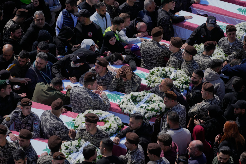 Colleagues mourn over the coffins during the funeral of 13 state security officers killed the previous day in an Israeli strike in the Lebanese coastal city of Sidon, Saturday, April 11, 2026. (AP Photo/Mohammed Zaatari)