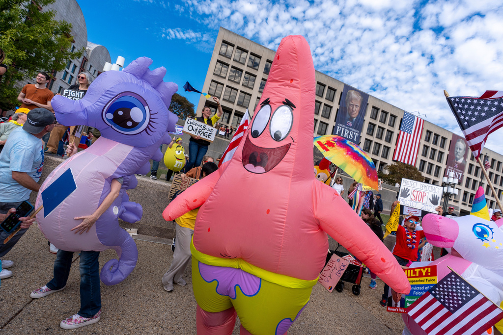 Demonstrators wear inflatable costumes and carry signs during a No Kings protest, Saturday, Oct. 18, 2025, in Washington. (AP Photo/Alex Brandon)