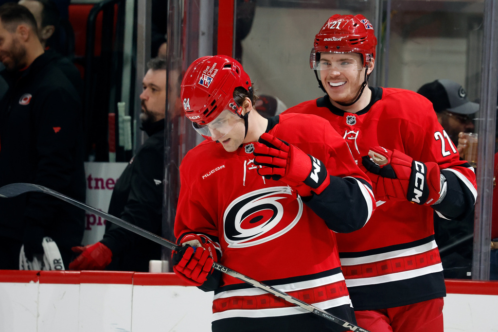 Carolina Hurricanes' Alexander Nikishin (21) picks on Joel Nystrom (64) after Nystrom scored his first NHL goal against the Chicago Blackhawks during the first period of an NHL hockey game in Raleigh, N.C., Thursday, Jan. 22, 2026. (AP Photo/Karl DeBlaker)