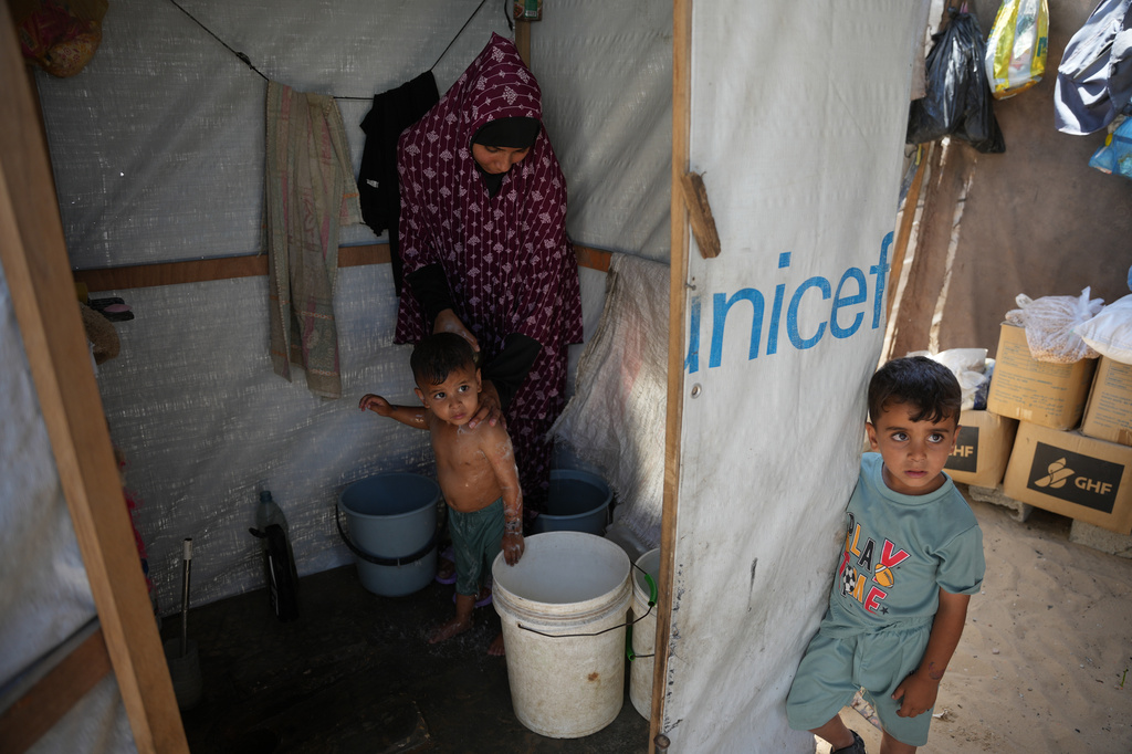 Iman Mansour bathes her son, Mohamed Shaban, in a makeshift bathroom beside her family's tent in Khan Younis, southern Gaza Strip, Wednesday, June 3, 2026. (AP Photo/Abdel Kareem Hana)