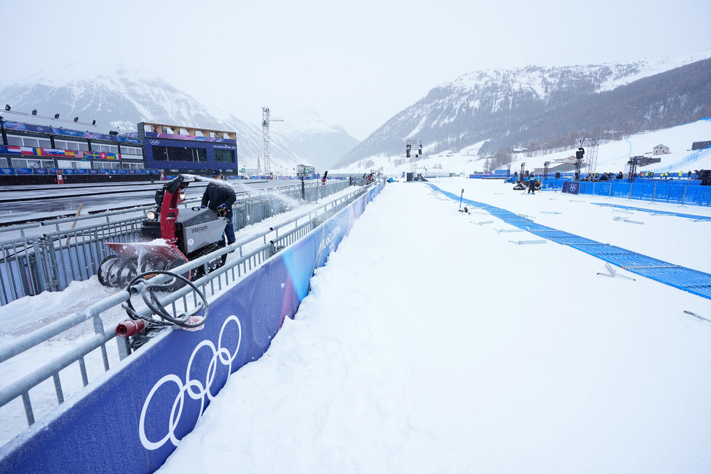 A worker blows snow off a path at the 2026 Winter Olympics, in Livigno, Italy, Wednesday, Feb. 4, 2026. (AP Photo/Gregory Bull)