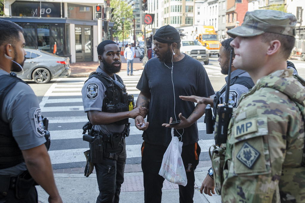 Members of the Mississippi National Guard watch as Metro Transit Police talk to a man after taking him off a Metro bus, as they patrol the Chinatown neighborhood in Washington, Thursday, Sept. 4, 2025. (AP Photo/Rod Lamkey, Jr.)