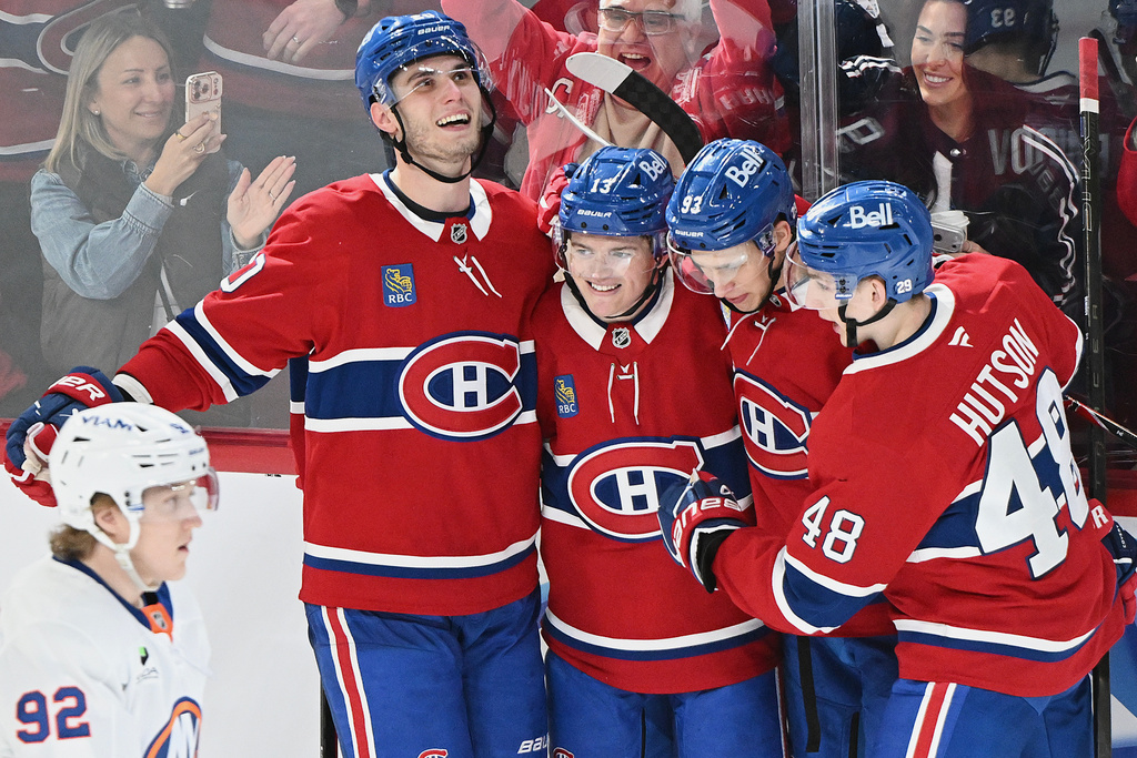 Montreal Canadiens' Cole Caufield (13) celebrates his third goal against the New York Islanders with teammates Juraj Slafkovsky (20), Ivan Demidov (93) and Lane Hutson (48) during the third period of an NHL hockey game in Montreal, Saturday, March 21, 2026. (Graham Hughes/The Canadian Press via AP)