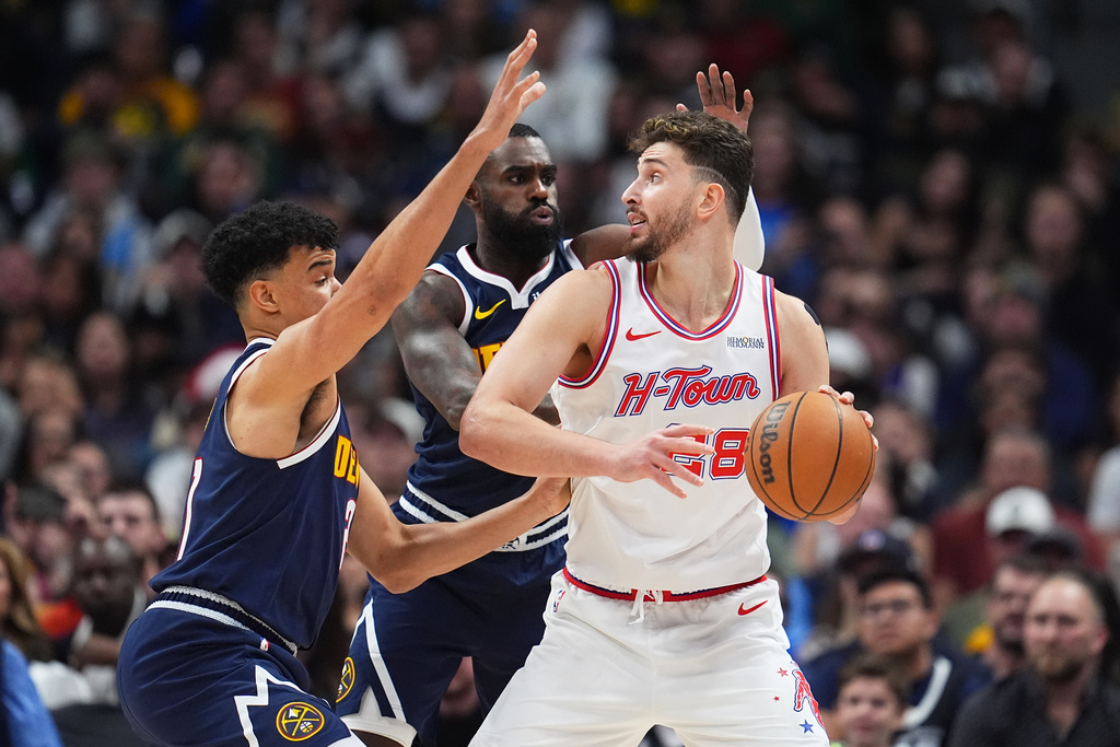 Houston Rockets center Alperen Sengun, right, looks to pass the ball as Denver Nuggets forward Spencer Jones, left, and guard Tim Hardaway Jr., center, defend in the first half of an NBA basketball game Monday, Dec. 15, 2025, in Denver. (AP Photo/David Zalubowski)