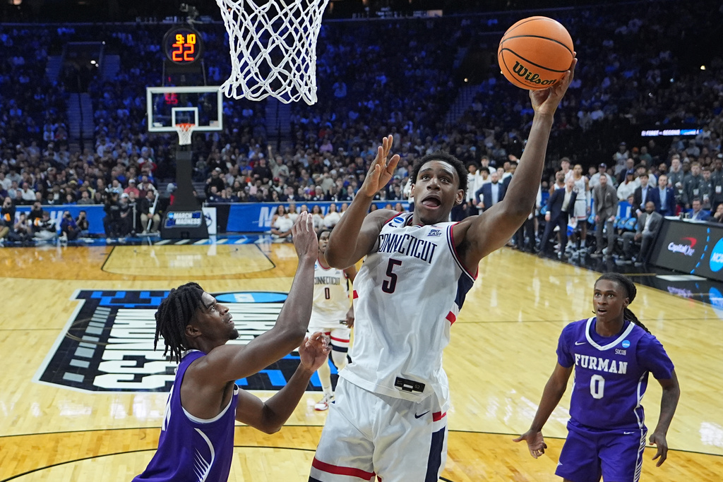 UConn's Tarris Reed Jr. (5) goes up to shoot against Furman's Cooper Bowser, left, during the first half in the first round of the NCAA college basketball tournament, Friday, March 20, 2026, in Philadelphia. (AP Photo/Matt Rourke)