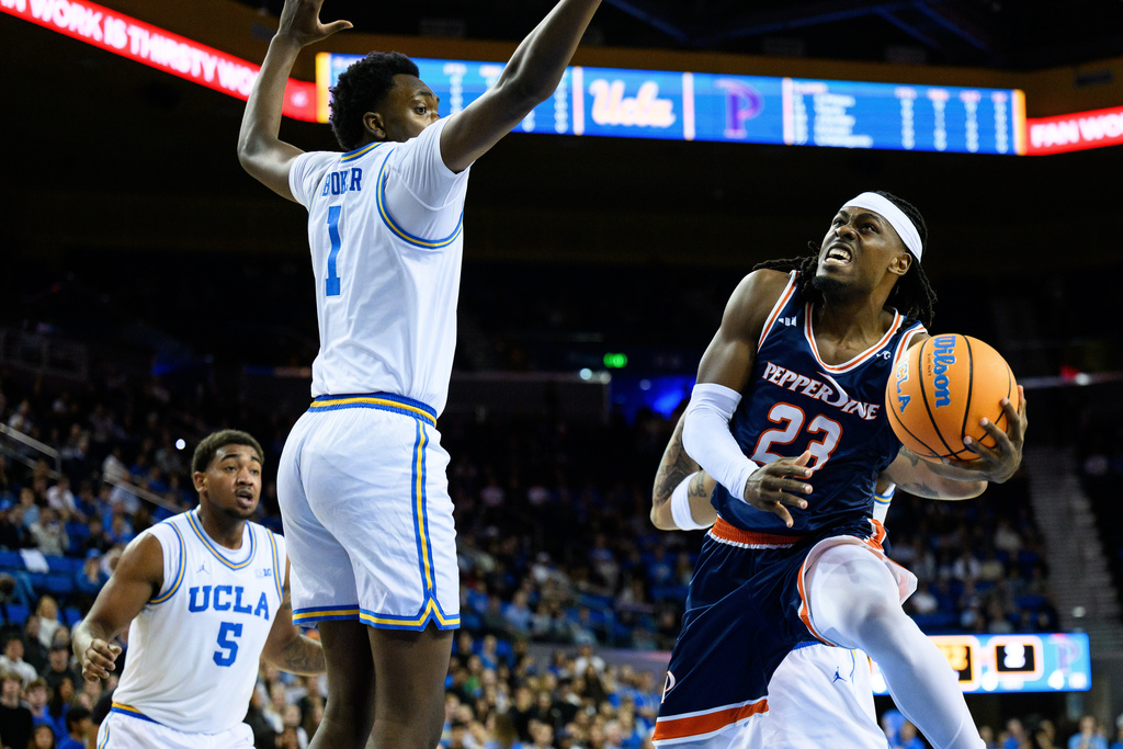 Pepperdine forward Javon Cooley (23) shoots past UCLA center Xavier Booker (1) during the first half of an NCAA college basketball game Friday, Nov. 7, 2025, in Los Angeles. (AP Photo/William Liang)