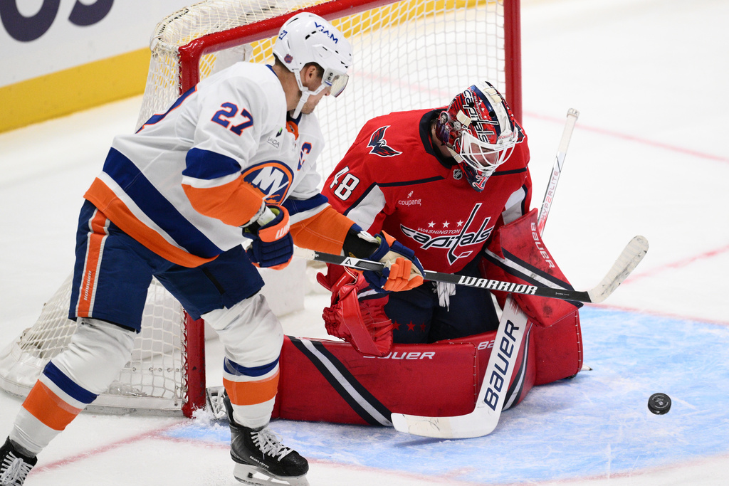 Washington Capitals goaltender Logan Thompson (48) and New York Islanders left wing Anders Lee (27) battle for the puck during the second period of an NHL hockey game, Friday, Oct. 31, 2025, in Washington. (AP Photo/Nick Wass)