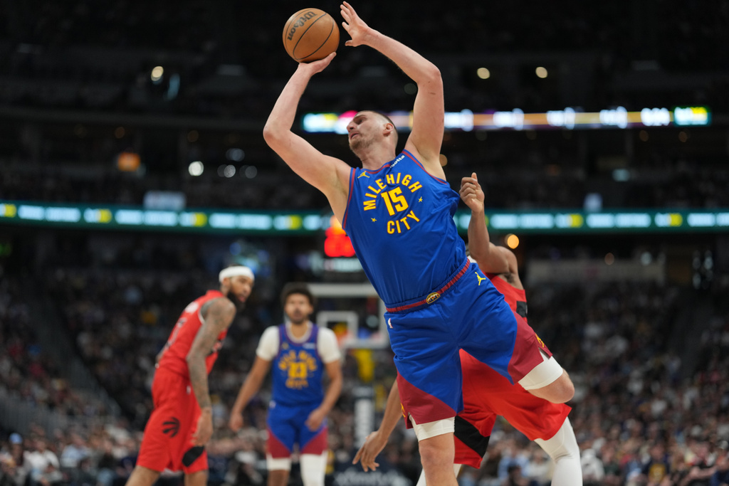 Denver Nuggets center Nikola Jokic, front, is fouled as he goes up for a shot by Toronto Raptors forward Scottie Barnes, not visible, in the first half of an NBA basketball game Friday, March 20, 2026, in Denver. (AP Photo/David Zalubowski)