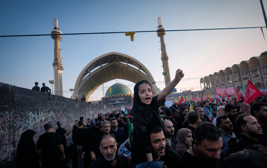 A little girl raises her fist from atop a man's shoulders as mourners gather during funeral ceremonies for slain Iranian Supreme Leader Ayatollah Ali Khamenei and members of his family at the Imam Khomeini Mosalla Grand Mosque in Tehran, Iran, Sunday, July 5, 2026. (AP Photo/Altaf Qadri)