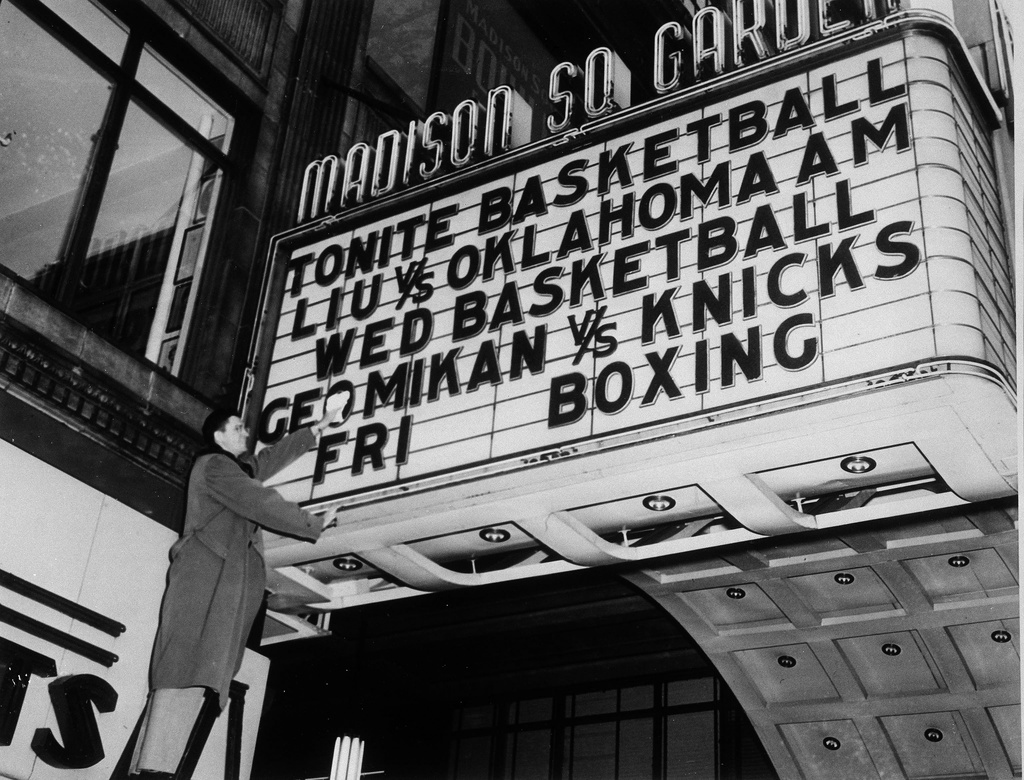 FILE - George Mikan of the Minneapolis Lakers polishes off the sign on the marquee of Madison Square Garden in New York, Dec. 13, 1949, to make sure his name shines brightly for tomorrow's game. (AP Photo/Jacob Harris, File)