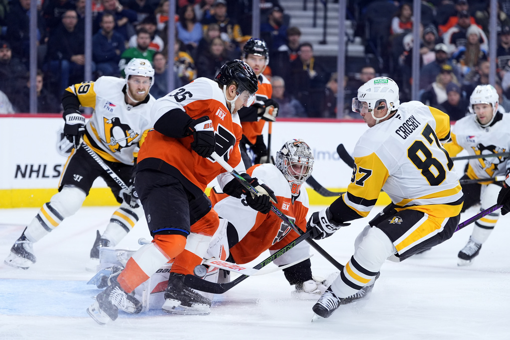 Pittsburgh Penguins' Sidney Crosby (87) scores a goal against Philadelphia Flyers' Dan Vladar (80) and Emil Andrae (36) during the first period of an NHL hockey game Monday, Dec. 1, 2025, in Philadelphia. (AP Photo/Matt Slocum)