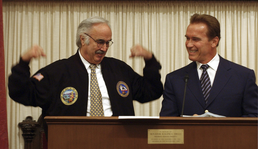FILE - State Sen. President Pro Tem John Burton, D-San Francisco, left, flexes his muscles for Gov. Arnold Schwarzenegger, after Schwarzenegger gave Burton a jacket as a going away gift during the last day of the Legislative session held at the Capitol in Sacramento, Calif., Friday, Aug. 27, 2004. (AP Photo/Rich Pedroncelli,File)