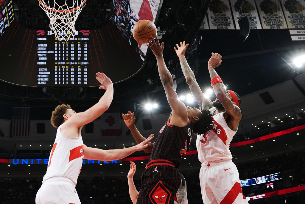 Chicago Bulls guard Collin Sexton, center, shoots against Toronto Raptors forward Jamison Battle, left, and forward Brandon Ingram during the first half of an NBA basketball game in Chicago, Wednesday, March 18, 2026. (AP Photo/Nam Y. Huh)