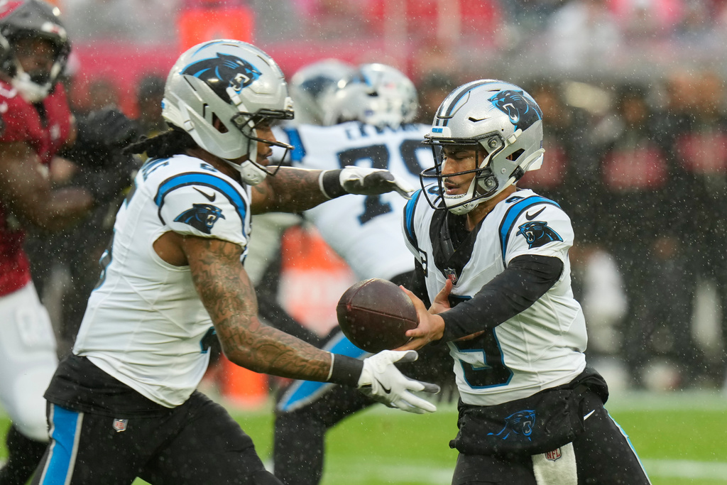 Carolina Panthers quarterback Bryce Young, right, hands off to running back Rico Dowdle (5) during the first half of an NFL football game Saturday, Jan. 3, 2026, in Tampa, Fla. (AP Photo/Chris O'Meara)