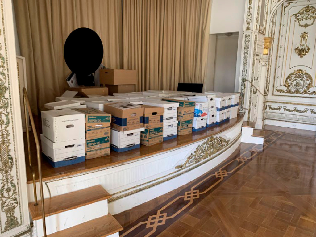 This image, contained in the indictment against former President Donald Trump, and partially redacted by source, shows boxes of records being stored on the stage in the White and Gold Ballroom at Trump's Mar-a-Lago estate in Palm Beach, Fla. (Justice Department via AP)