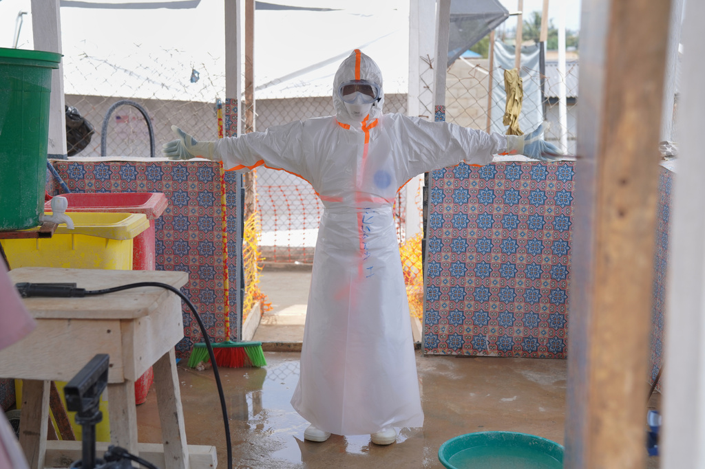 A health worker waits to be sprayed with disinfectant at the treatment centre in Bunia General Hospital in Ituri, eastern Congo, Tuesday, Aug. 11, 2026. (AP Photo/Dieudonne Dirole)