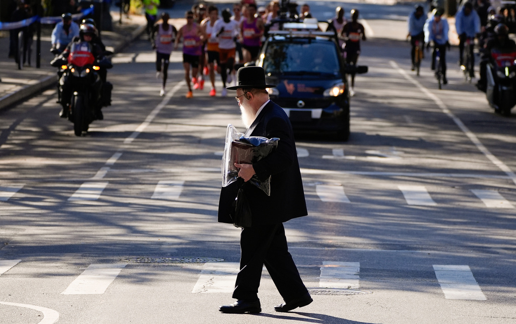 FILE - An Orthodox Jewish man crosses the street as athletes in the men's elite division make their way through Brooklyn during the New York City Marathon, Nov. 2, 2025, in New York. (AP Photo/Yuki Iwamura, File)
