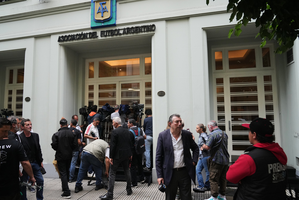 Journalists gather outside the Argentine Soccer Association (AFA) headquarters being raided as part of a judicial investigation into links authorities allege AFA has with a financial services company being investigated for alleged money laundering in Buenos Aires, Argentina, Tuesday, Dec. 9, 2025. (AP Photo/Rodrigo Abd)