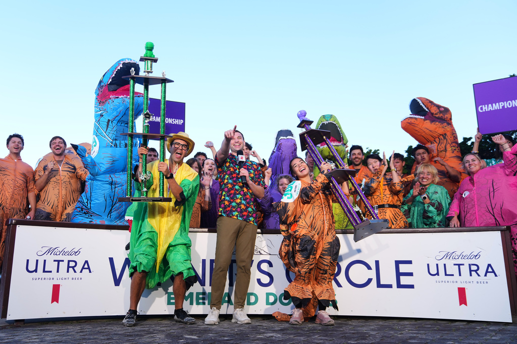 Chase Mertz, of Seattle, and "Tiny Rex," Mimi Miyazawa, of Orem, Utah, celebrate with their men's and women's championship trophies after competing in the T-Rex World Championship Races at Emerald Downs, Sunday, July 12, 2026, in Auburn, Wash. (AP Photo/Lindsey Wasson)