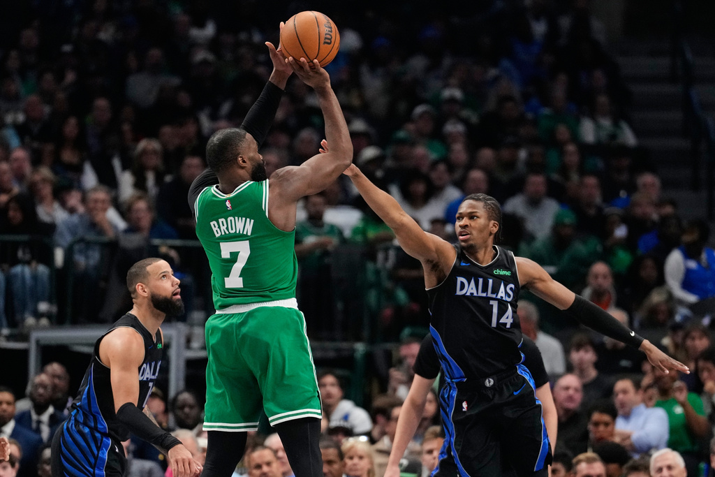 Boston Celtics guard Jaylen Brown (7) shoots as Dallas Mavericks' Caleb Martin, left, and Miles Kelly (14) defend in the first half of an NBA basketball game Tuesday, Feb. 3, 2026, in Dallas. (AP Photo/Tony Gutierrez)