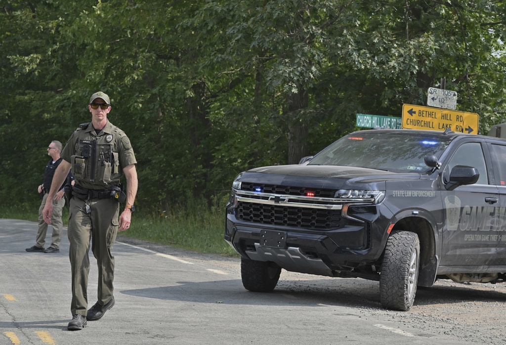 Police officers block the street leading to where two Pennsylvania state troopers were ambushed and shot Thursday, Aug. 7, 2025, near the village of Thompson in Susquehanna County, Pa. (AP Photo/Aimee Dilger)