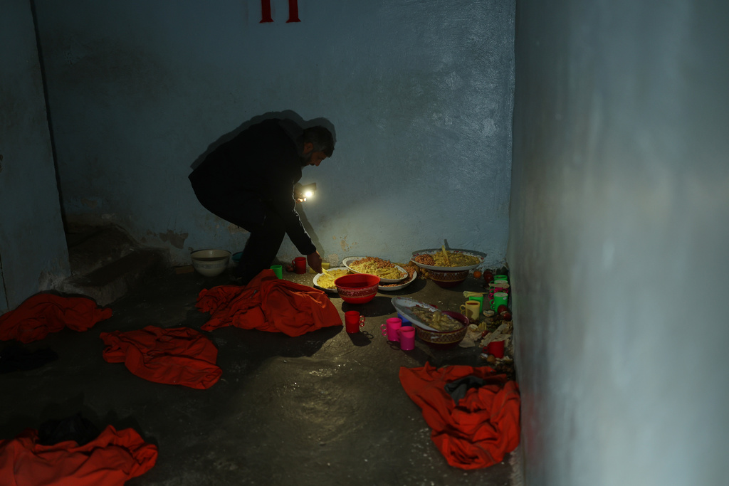 A Syrian government fighter inspects food left behind inside a prison cell, where red detainee suits lie on the floor, in the town of Shaddadeh, northeastern Syria, Tuesday, Jan. 20, 2026, a day after Syria's Interior Ministry said Islamic State group members escaped from the facility during clashes with the Kurdish-led Syrian Democratic Forces. (AP Photo/Ghaith Alsayed)