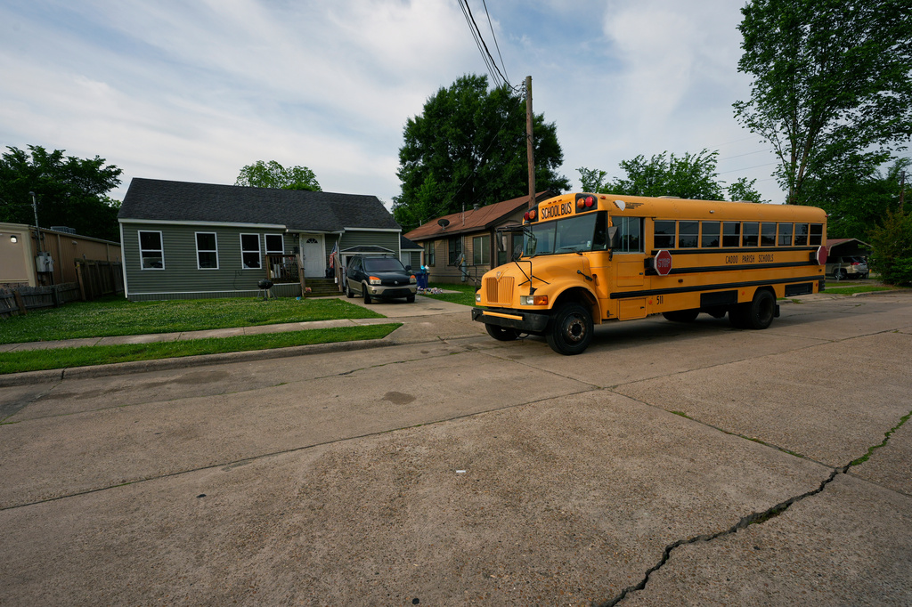A school bus passes the house where 8 children were killed during a mass shooting the day before in Shreveport, La., Monday, April 20, 2026. (AP Photo/Gerald Herbert)