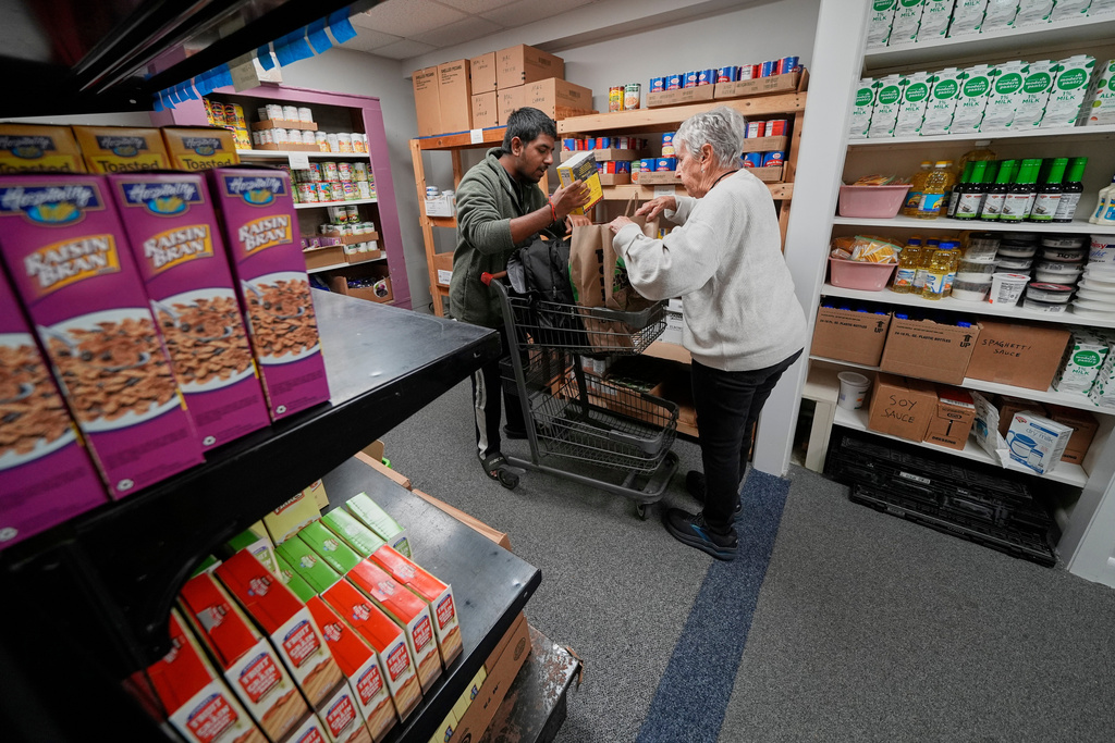 FILE - Volunteer Betty McNeely, right, helps a man bag food items at Project Feed, an emergency food pantry in Portland, Maine, Oct. 28, 2025. (AP Photo/Robert F. Bukaty, File)