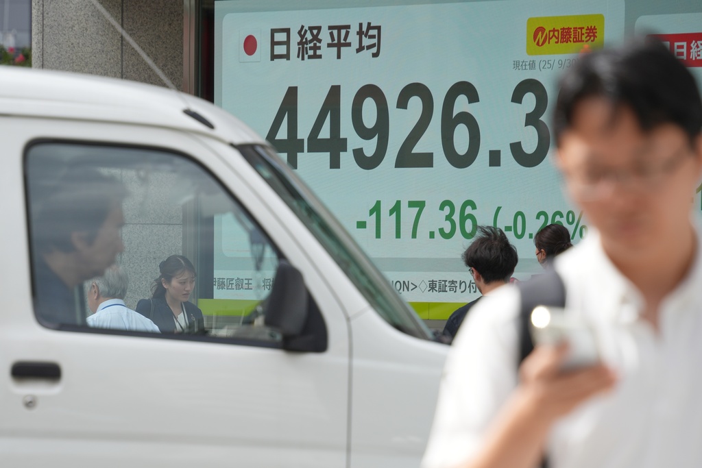 People walk in front of an electronic stock board showing Japan's Nikkei 225 index at a securities firm Tuesday, Sept. 30, 2025, in Tokyo. (AP Photo/Eugene Hoshiko)