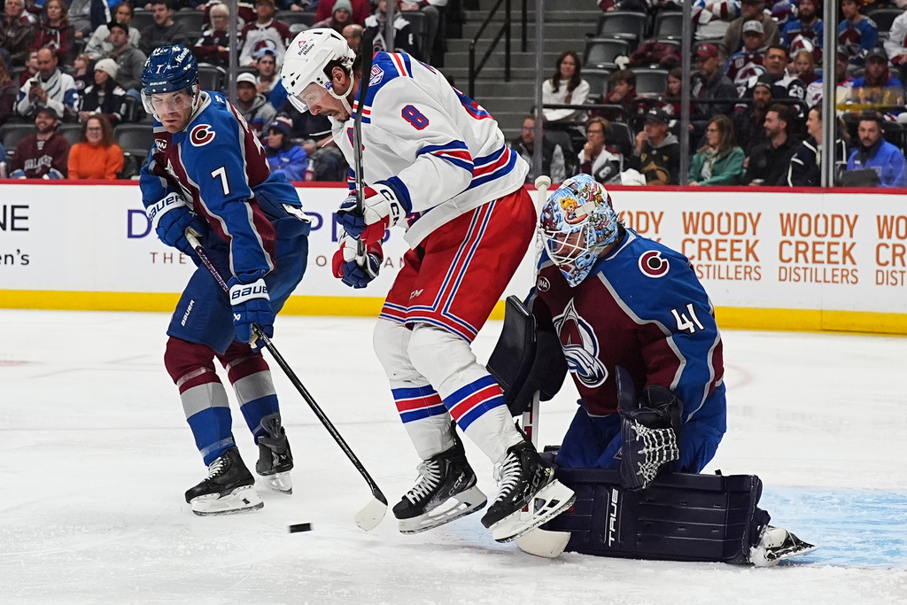 New York Rangers center J.T. Miller, center, tries to redirect the puck past Colorado Avalanche goaltender Scott Wedgewood, right, as defenseman Devon Toews covers in the second period of an NHL hockey game Thursday, Nov. 20, 2025, in Denver. (AP Photo/David Zalubowski)