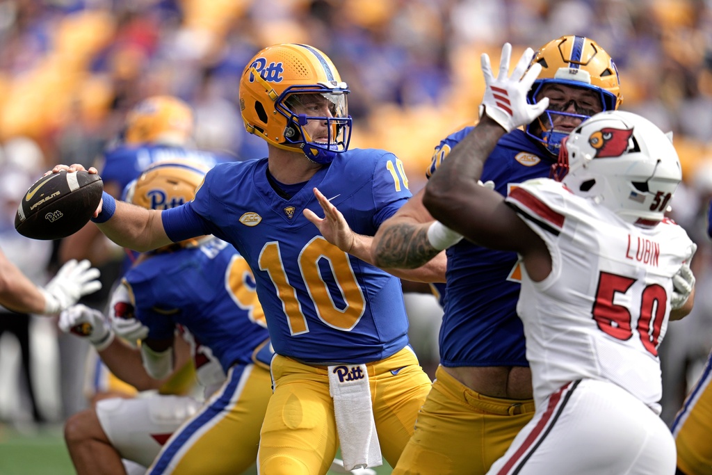 Pittsburgh quarterback Eli Holstein (10) throws a pass under pressure by Louisville Cardinals defensive lineman as Pittsburgh offensive lineman Ryan Baer (70) blocks during the first half of an NCAA college football game in Pittsburgh, Saturday, Sept. 27, 2025. (AP Photo/Gene J. Puskar)