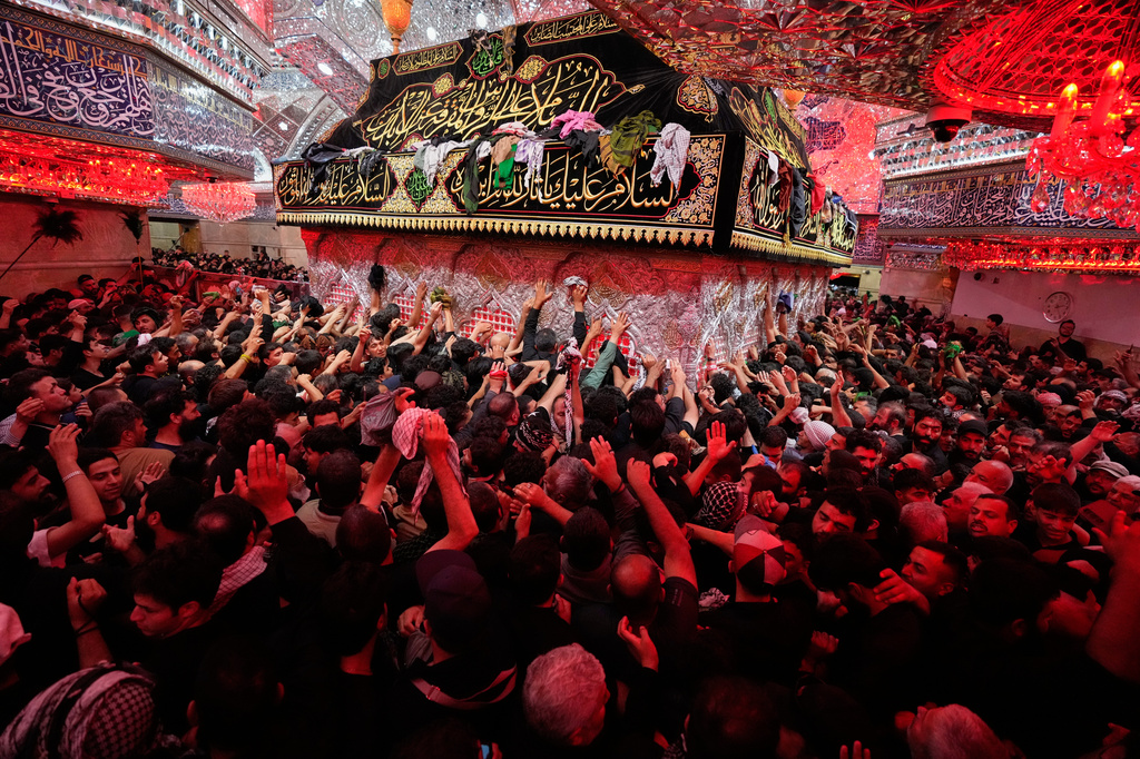Shiite Muslim worshippers reach out to touch the shrine surrounding the tomb of Imam Hussein ahead of Arbaeen, the annual Shiite commemoration marking 40 days after Ashoura, at the Imam Hussein Shrine in Karbala, Iraq, Monday, Aug. 3, 2026. (AP Photo/Hadi Mizban)