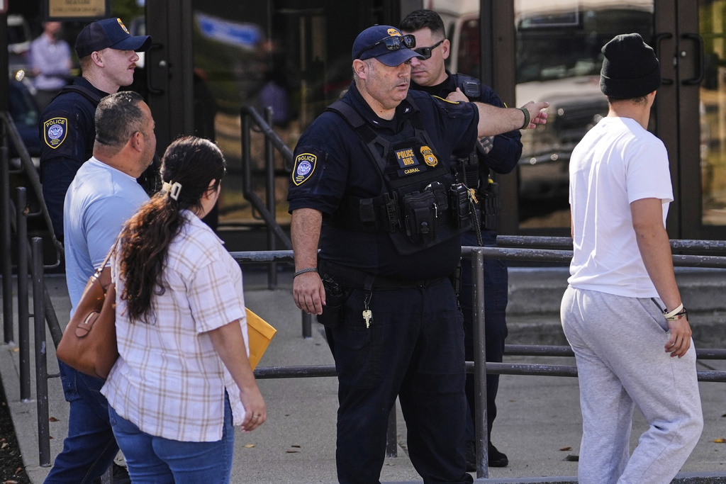 A Department of Homeland Security police officer directs visitors towards the front door of the U.S. Immigration and Customs Enforcement regional field office, Tuesday, Sept. 16, 2025, in Burlington, Mass. (AP Photo/Charles Krupa)