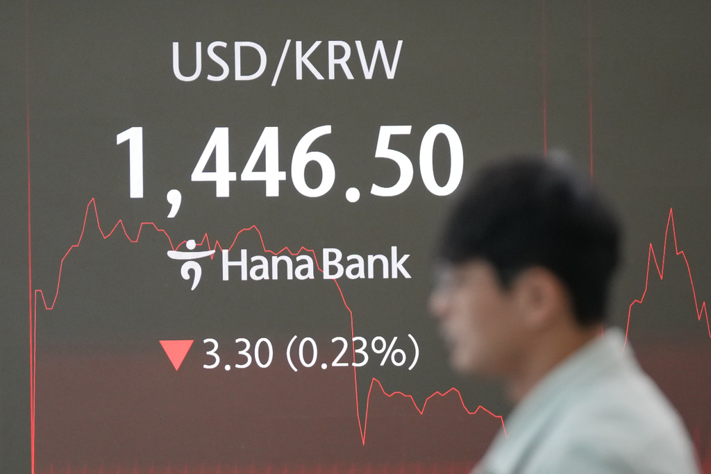 A dealer walks past near the screen showing the foreign exchange rate between U.S. dollar and South Korean won at a dealing room of Hana Bank in Seoul, South Korea, Friday, Dec. 26, 2025. (AP Photo/Lee Jin-man)