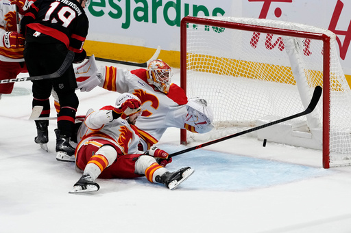 Calgary Flames goaltender Devin Cooley, top right, and Mackenzie Weegar, bottom right, watcha shot by Ottawa Senators' Jake Sanderson (not shown) go into the net during third-period NHL hockey game action in Ottawa, Ontario, Thursday, Oct. 30, 2025. (Justin Tang/The Canadian Press via AP) Calgary Flames goaltender Devin Cooley, top right, and Mackenzie Weegar, bottom right, watcha shot by Ottawa Senators' Jake Sanderson (not shown) go into the net during third-period NHL hockey game action in Ottawa, Ontario, Thursday, Oct. 30, 2025. (Justin Tang/The Canadian Press via AP)