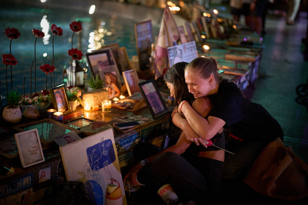 Yuval Miranda and Katya Emelianova cry as they embrace next to the photographs of Israelis who were killed in the deadly Oct. 7, 2023 Hamas attack on Israel, at a memorial marking the two year anniversary of the assault, in Tel Aviv, Israel, Tuesday, Oct. 7, 2025. (AP Photo/Emilio Morenatti)