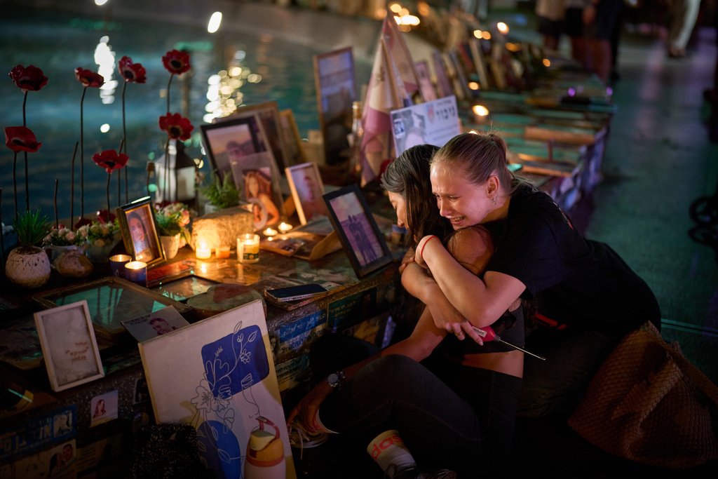 Yuval Miranda and Katya Emelianova cry as they embrace next to the photographs of Israelis who were killed in the deadly Oct. 7, 2023 Hamas attack on Israel, at a memorial marking the two year anniversary of the assault, in Tel Aviv, Israel, Tuesday, Oct. 7, 2025. (AP Photo/Emilio Morenatti)
