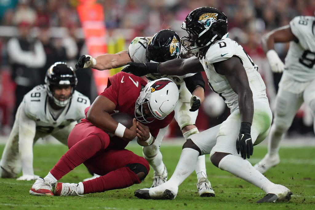 Jacksonville Jaguars linebacker Devin Lloyd (0) and linebacker Dennis Gardeck (47) sack Arizona Cardinals quarterback Jacoby Brissett (7) during the second half of an NFL football game Sunday, Nov. 23, 2025, in Glendale, Ariz. (AP Photo/Rick Scuteri)