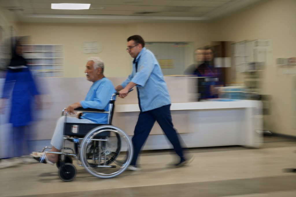 A patient in a wheelchair is pushed along a corridor at Shohadaye Tajrish Hospital in Tehran, Iran, Tuesday, April 7, 2026. (AP Photo/Francisco Seco)