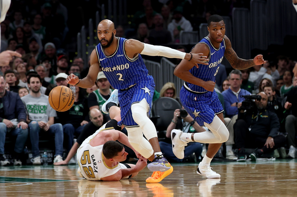 Boston Celtics forward Luka Garza (52) falls to the court as Orlando Magic guard Jevon Carter (2) and forward Jamal Cain (8) take control of the ball during the second half of an NBA basketball game, Sunday, April 12, 2026, in Boston. (AP Photo/Mark Stockwell)