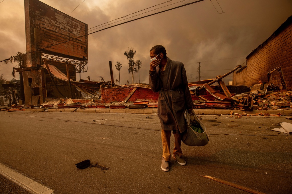 A man walks past a fire-ravaged business after the Eaton Fire swept through, Jan. 8, 2025, in Altadena, Calif. (AP Photo/Ethan Swope, File)