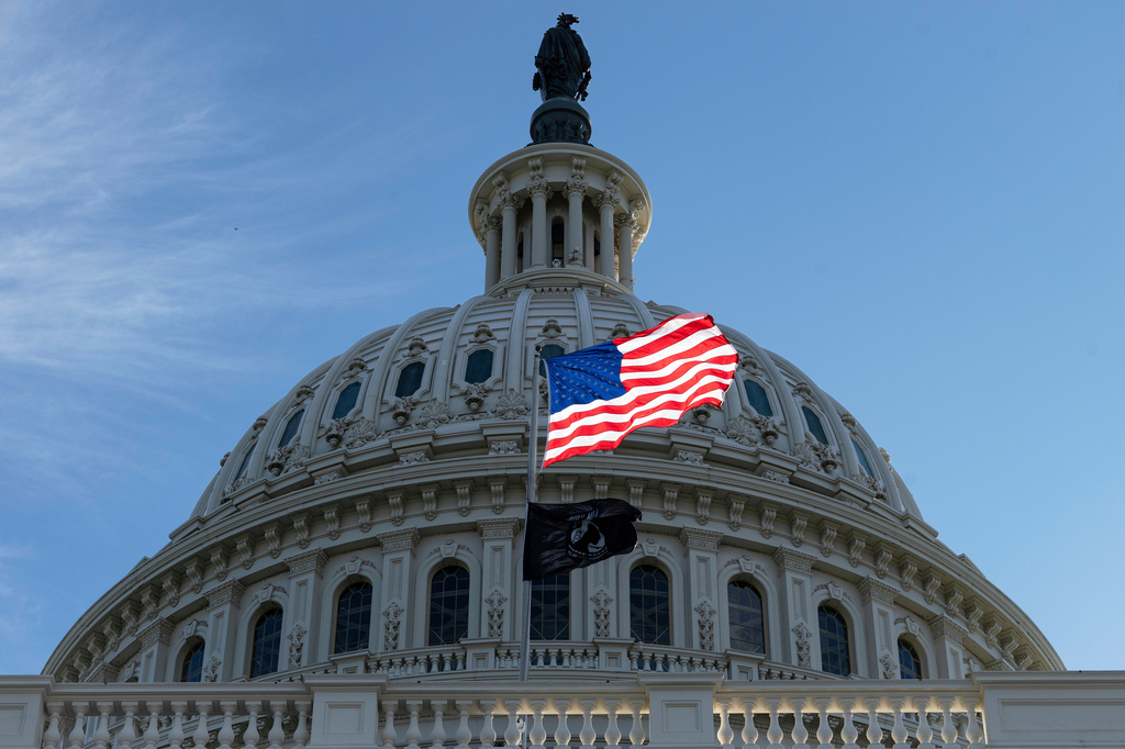 FILE - The American flag over the Capitol is illuminated by the early morning light in Washington, Oct. 1, 2025. (AP Photo/J. Scott Applewhite, File)