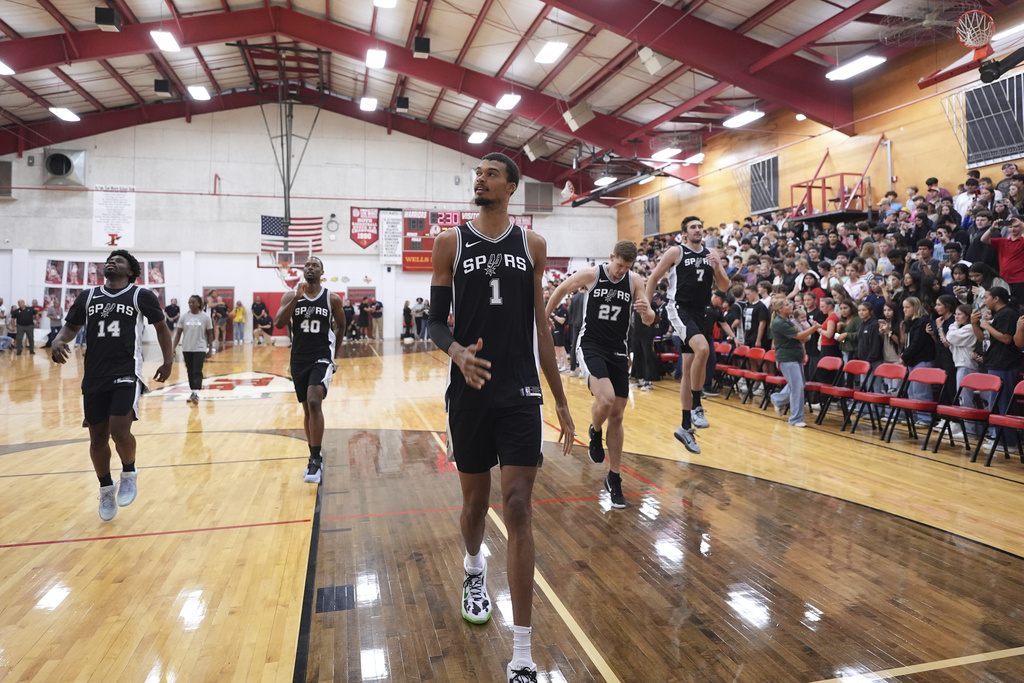 San Antonio Spurs center Victor Wembanyama (1) and teammates make a surprise visit to Tom Moore High School, Wednesday, Sept. 10, 2025, in Ingram, Texas, to visit the students and families of those impacted by flooding that killed more than 130 people across the region. (AP Photo/Eric Gay)