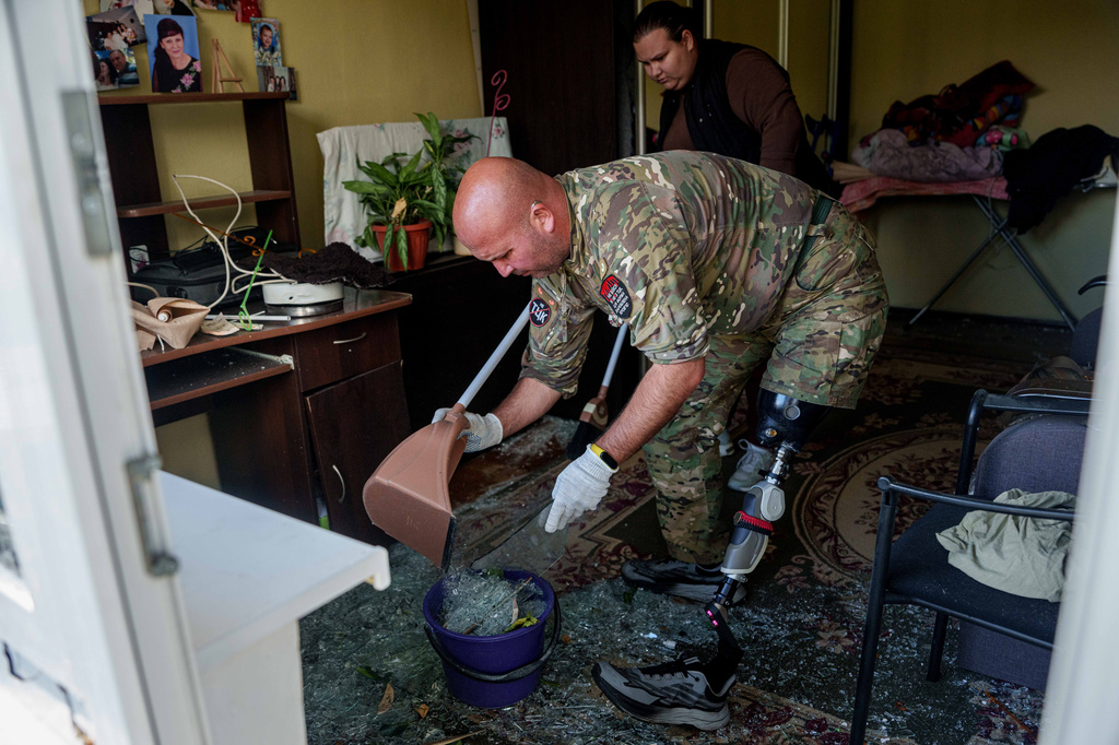 Oleksii, a Ukrainian war veteran, clears broken glass inside an apartment building damaged by a Russian drone strike in Kyiv, Ukraine, Tuesday, Sept. 22, 2026. (AP Photo/Evgeniy Maloletka)